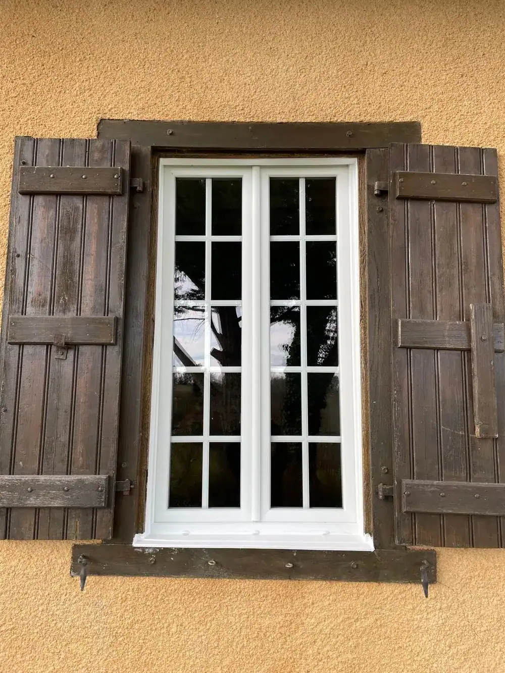Fenêtre PVC blanche à petits bois avec volets bois, maison gasconne